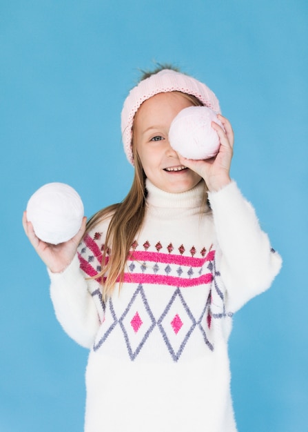 Niña rubia que cubre su rostro con una bola de nieve