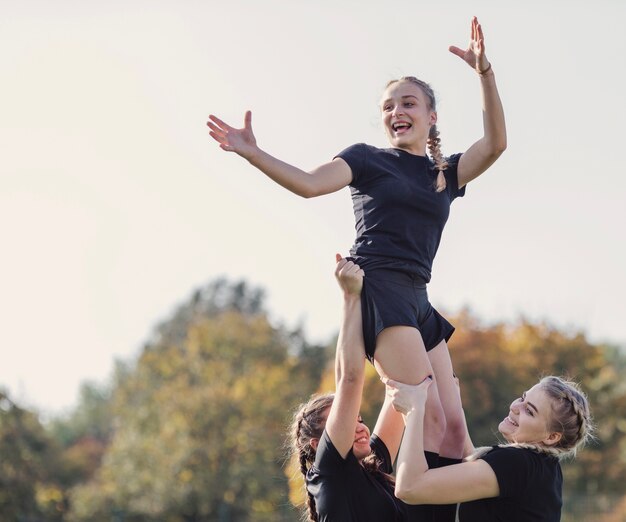 Niña rubia sonriente criada por sus compañeros de equipo