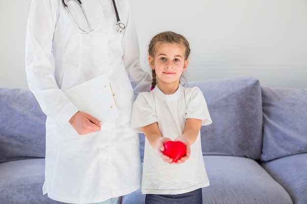 Niña rubia sosteniendo corazón con doctora