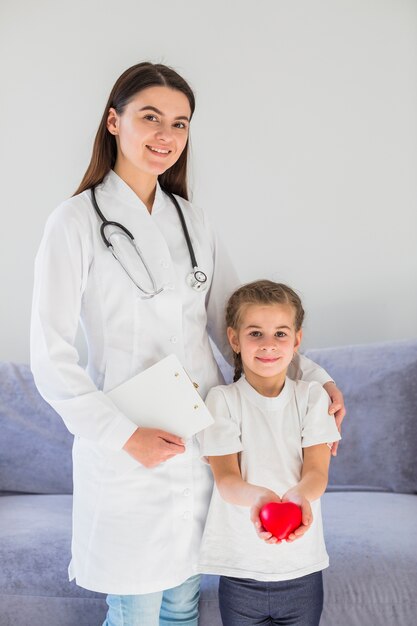 Niña rubia sosteniendo corazón con doctora