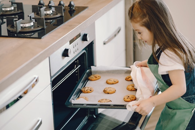 Foto gratuita niña saca una bandeja de galletas del horno