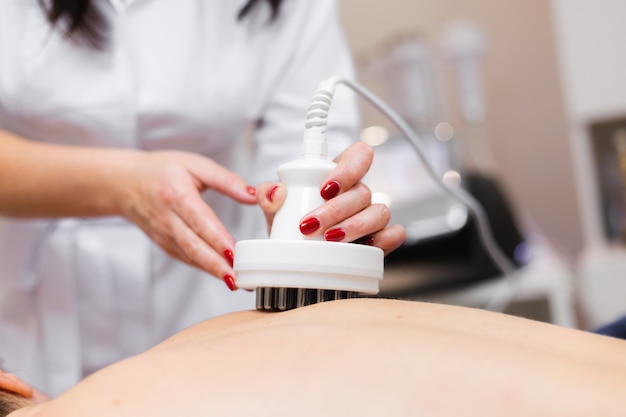 La niña en el salón de spa recibe un masaje de espalda y cuello, se acuesta en la mesa de cosmetología, se relaja y disfruta del proceso.