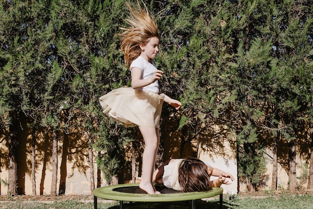 Niña saltando en trampolín cerca de la mentira hermana