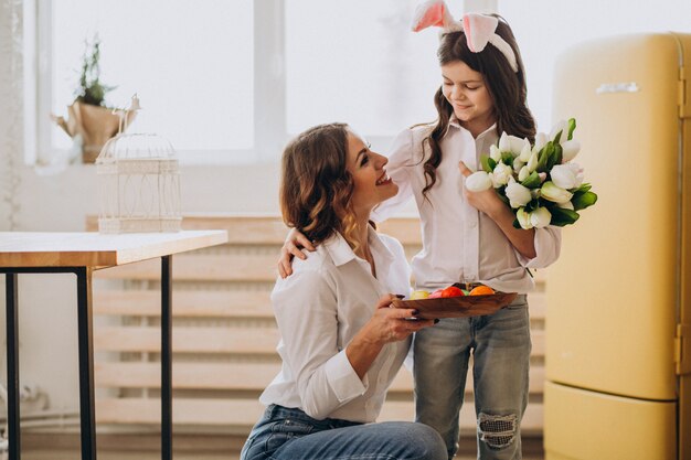 Niña saludando a la madre con flores en el día de la madre