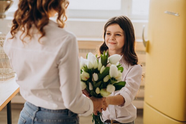 Niña saludando a la madre con flores en el día de la madre