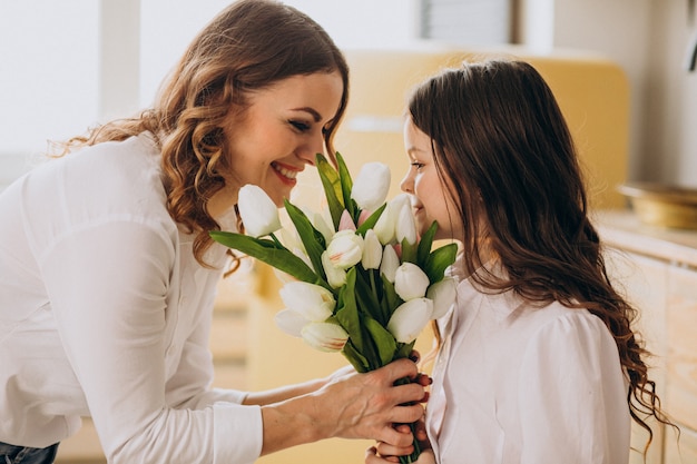 Niña saludando a la madre con flores en el día de la madre