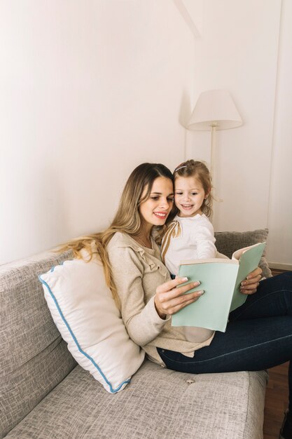 Niña señalando un libro mientras leía con mamá