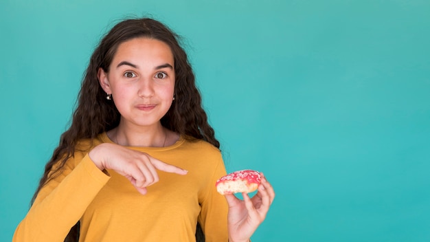 Foto gratuita niña señalando una rosquilla glaseada