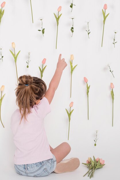 Foto gratuita niña señalando la vista posterior de tulipán