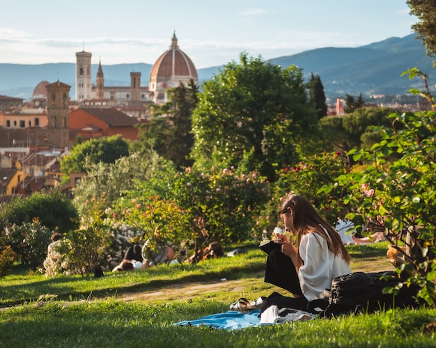 Niña sentada en el césped con una hermosa vista de Florencia