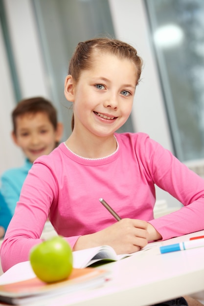 Niña sentada con compañero de clase de fondo