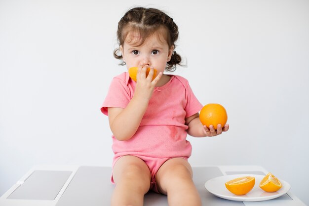 Niña sentada y disfrutando de sus naranjas