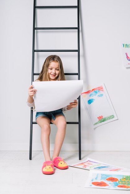 Niña sentada en escalera con dibujos.