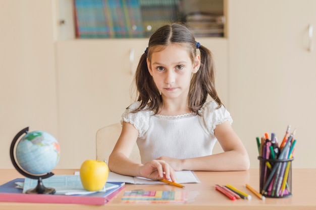 Niña sentada en el escritorio en el aula