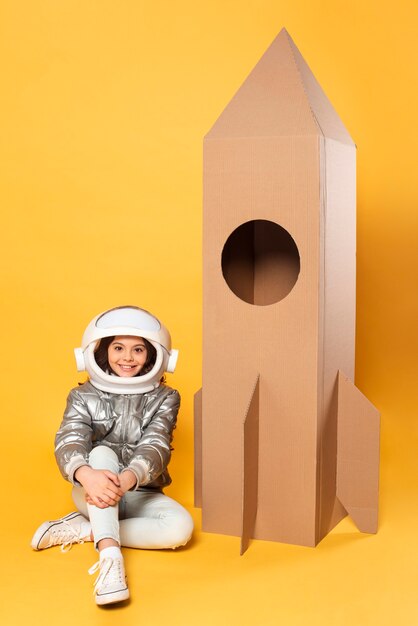 Niña sentada junto a la nave espacial de juguete de dibujos animados