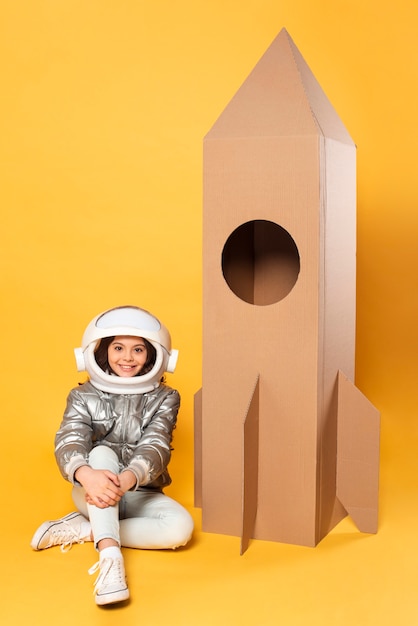 Niña sentada junto a la nave espacial de juguete de dibujos animados