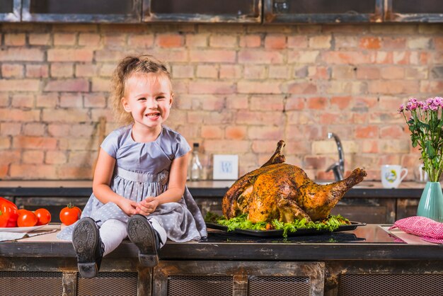 Niña sentada en la mesa con pavo asado