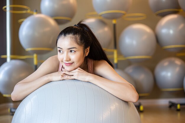 La niña sentada relajarse con la pelota en el gimnasio.