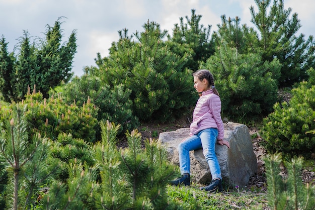 Niña sentada en una roca al aire libre