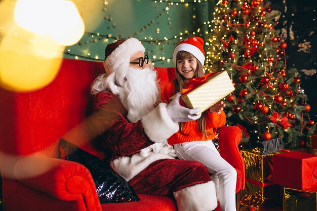 Niña sentada con santa y regalos en navidad