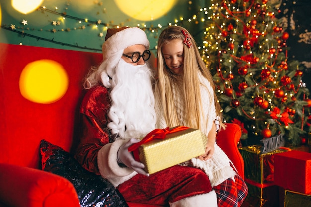 Niña sentada con santa y regalos en navidad