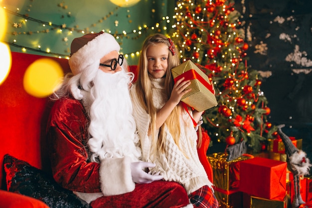 Niña sentada con santa y regalos en navidad