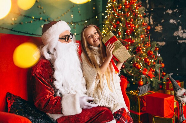 Niña sentada con santa y regalos en navidad