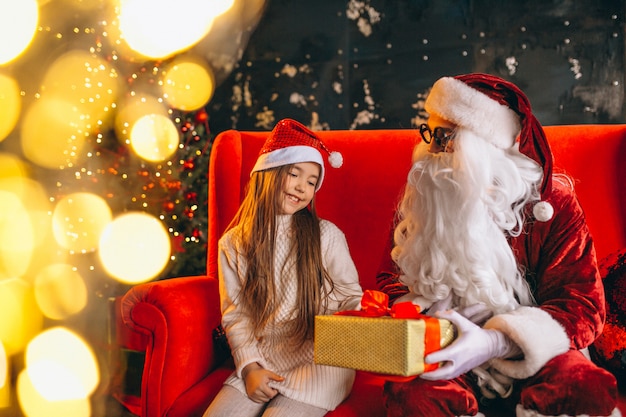 Niña sentada con santa y regalos en navidad