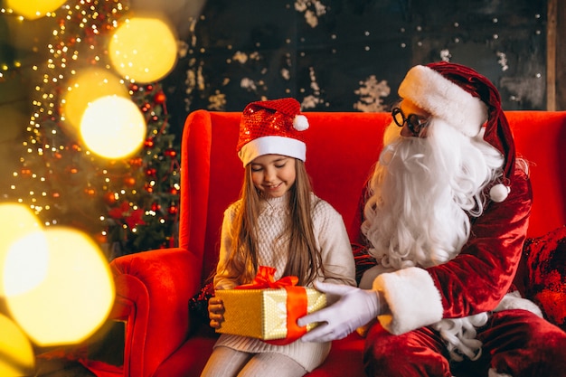 Niña sentada con santa y regalos en navidad