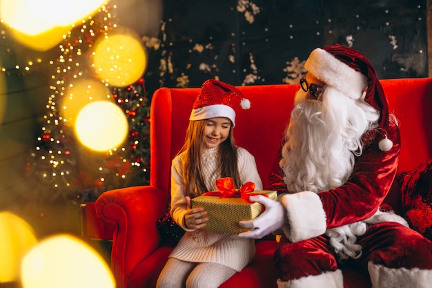 Niña sentada con santa y regalos en navidad