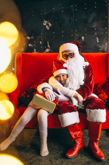 Niña sentada con santa y regalos en navidad