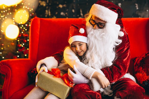 Niña sentada con santa y regalos en navidad