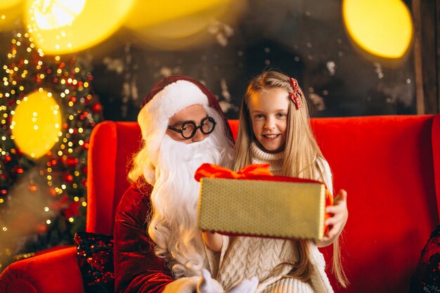 Niña sentada con santa y regalos en navidad