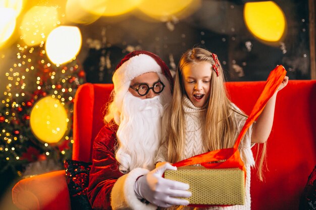 Niña sentada con santa y regalos en navidad