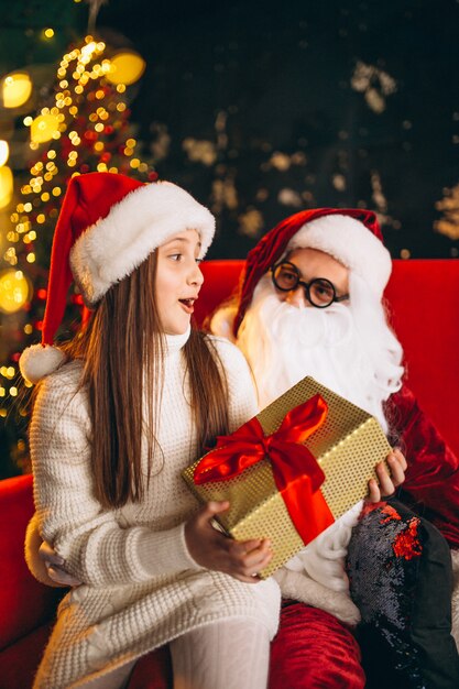 Niña sentada con santa y regalos en navidad