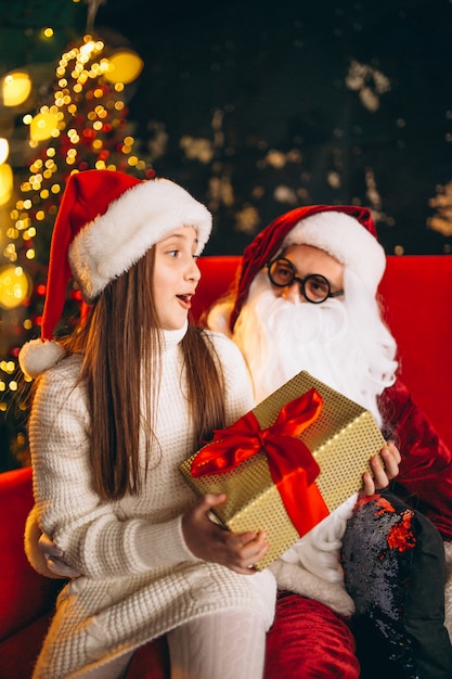 Niña sentada con santa y regalos en navidad