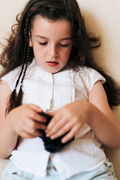 Niña sentada en el sofá con cámara de fotos