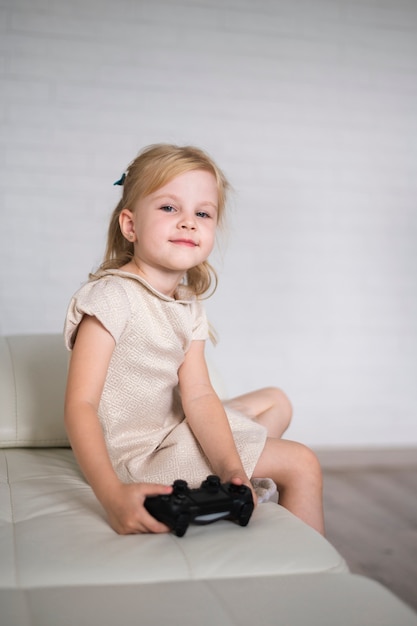 Niña sentada en el sofá con joystick