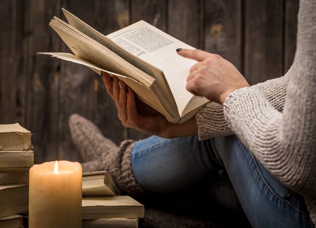 niña sentada en el suelo rodeada de muchos libros blancos y una vela grande