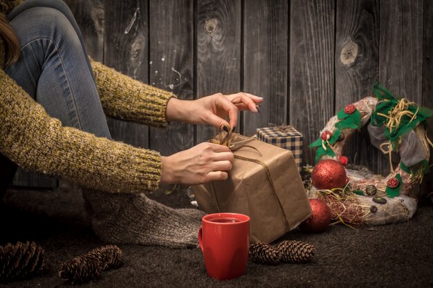 niña sentada en el suelo con una taza roja en la mano, rodeada de adornos navideños