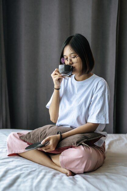 Una niña sentada y tomando café en el dormitorio.