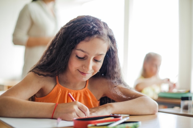 Niña, sentado, escritorio, tenencia, lápiz