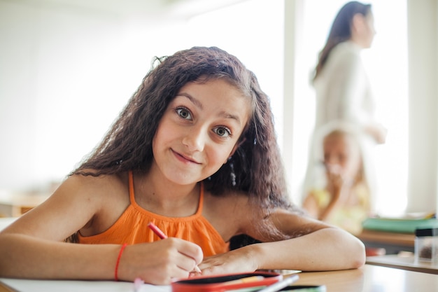 Niña, sentado, escritorio, tenencia, lápiz