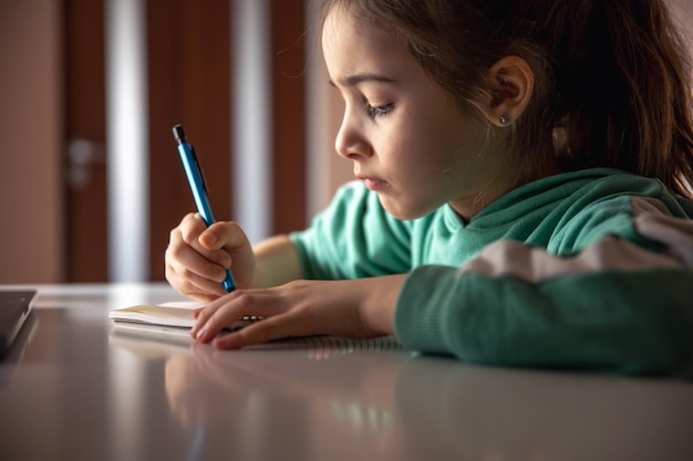 Foto gratuita niña seria escribe con un bolígrafo en un cuaderno