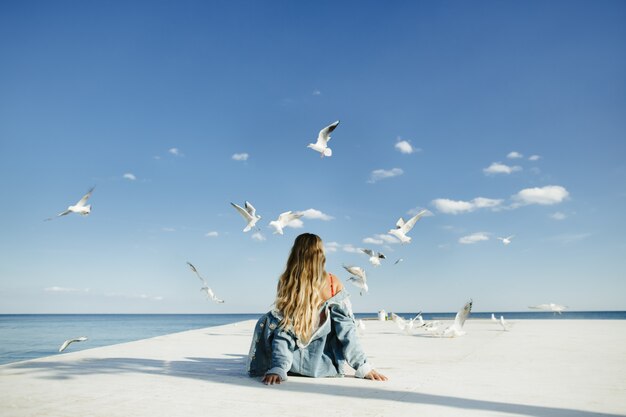 una niña se sienta en la litera y observa a las gaviotas