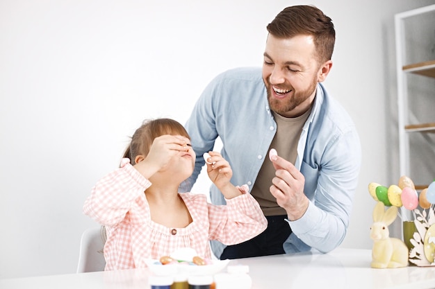 Niña con síndrome de Down y su padre jugando con huevos de colores de Pascua