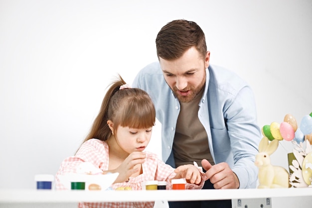 Niña con síndrome de Down y su padre jugando con huevos de colores de Pascua