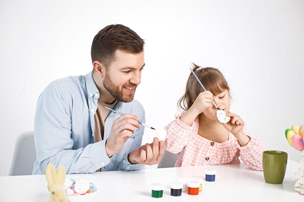 Niña con síndrome de Down y su padre pintando huevos de colores de Pascua