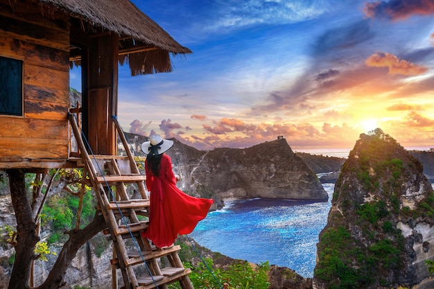 Niña sobre los pasos de la casa en el árbol al amanecer en la isla de Nusa Penida, Bali en Indonesia