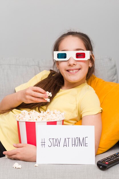 Foto gratuita niña en el sofá comiendo palomitas de maíz